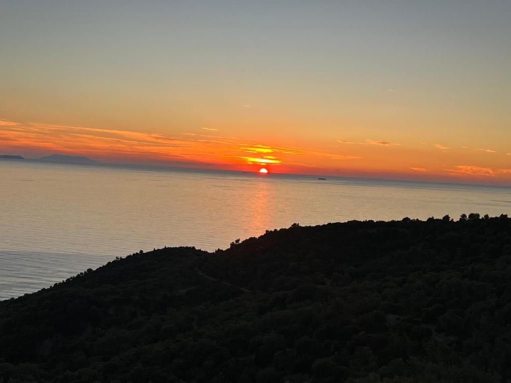 a sunset over the water and a hill with the sun setting at Hotel Piqeras Kris in Piqeras
