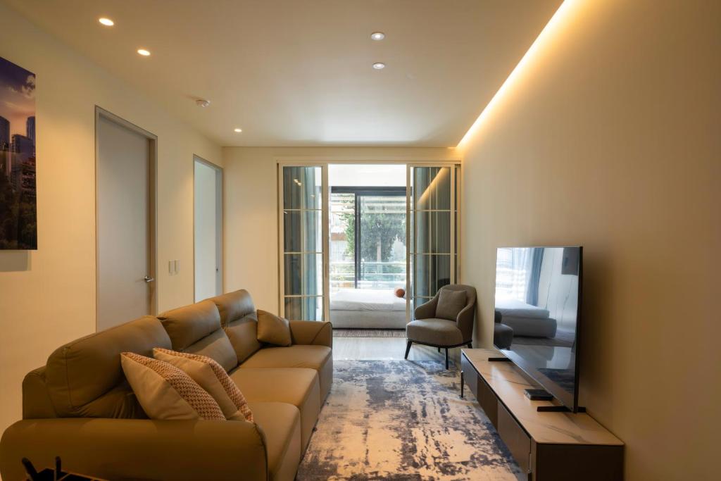 a living room with a couch and a flat screen tv at Poe 227 By Ömora in Mexico City