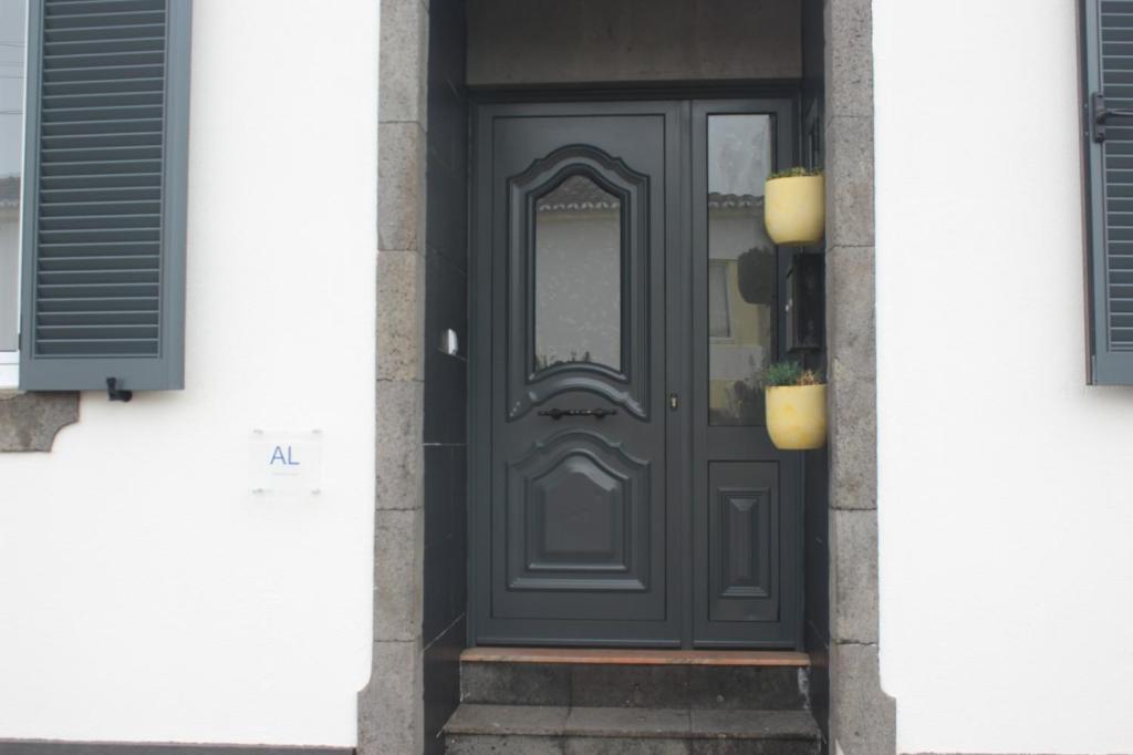 a black door on a house with a window at Casa do Tempo in Achada