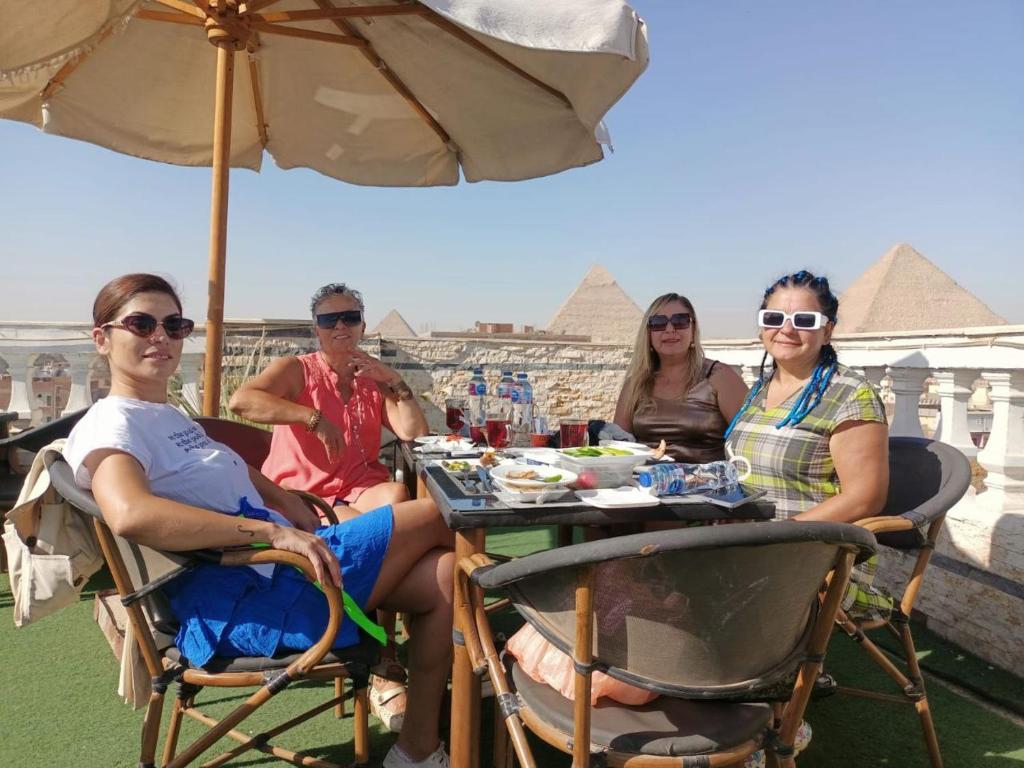a group of people sitting at a table under an umbrella at Star View Pyramids Hostel in Nazlet el-Sîsi