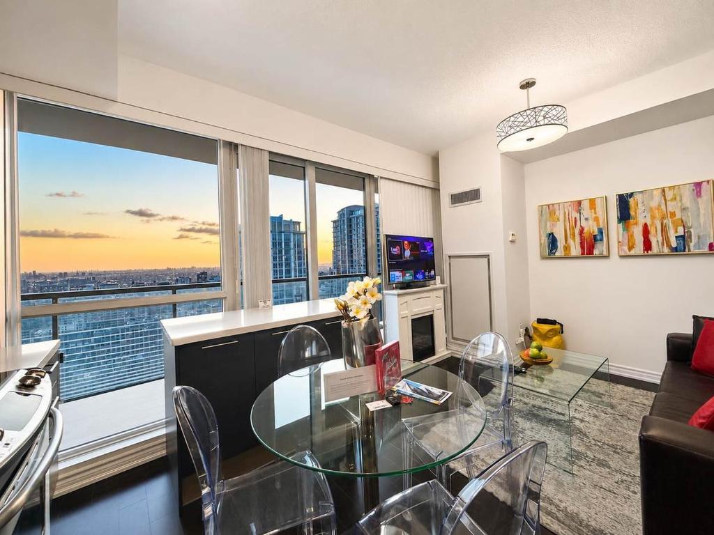 a living room with a glass table and a large window at Altitude Suites on Yonge - Downtown Toronto Short Walk to SickKids, TMU & Eaton Centre in Toronto
