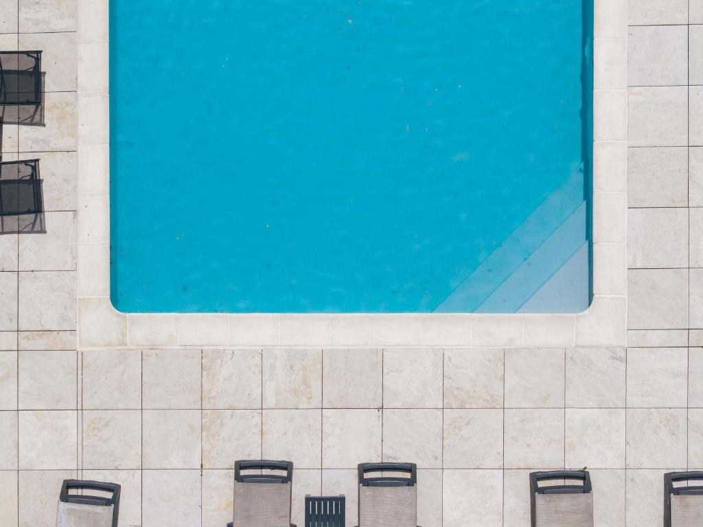 four chairs in front of a swimming pool at Mercure Annecy Sud in Annecy