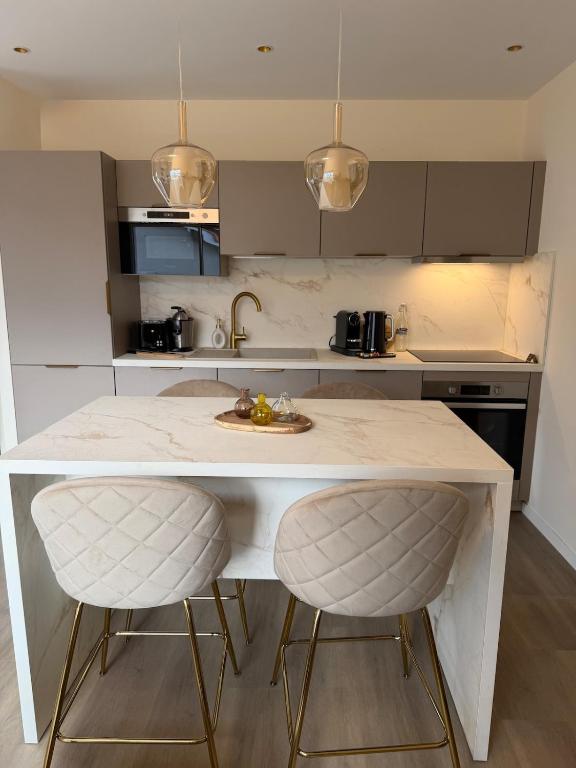 a kitchen with a counter with two bar stools at Marathi élégance T2 neuf avec SPA privatif in Biscarrosse