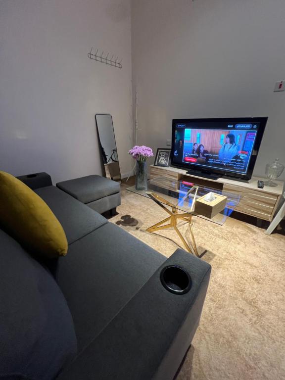 a living room with a couch and a flat screen tv at شالية ريفي الفندقي هادي وسط المدينة in Az Zulfi