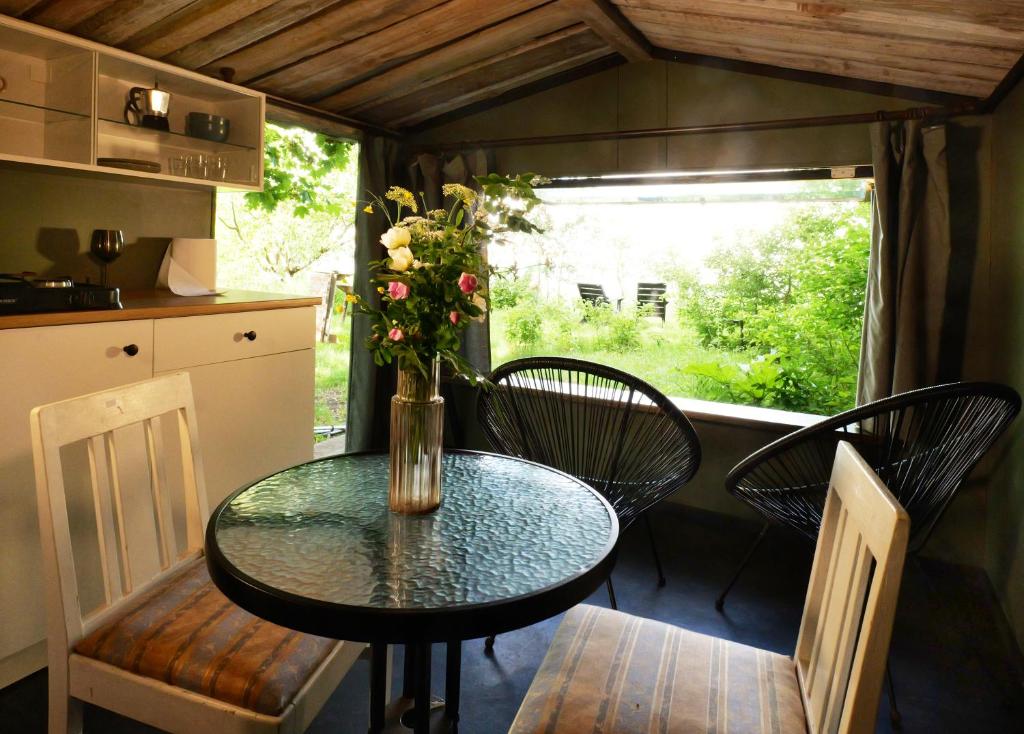 a table with chairs and a vase with flowers on it at Minimalist riverside hideout in Riga