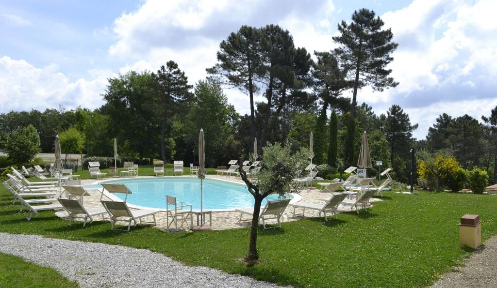 una piscina con tumbonas y un árbol en el césped en Tuscany Country Apartments, en Gambassi Terme