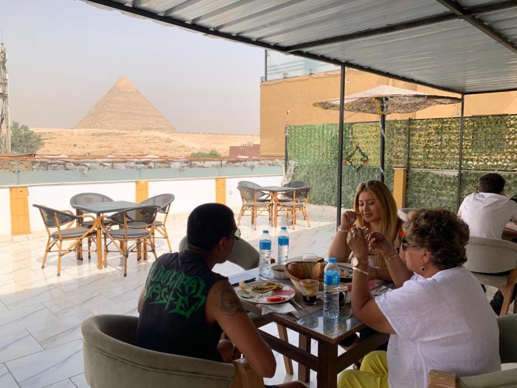 a group of people sitting at a table with a pyramid in the background at Basha Pyramids Best View in Giza