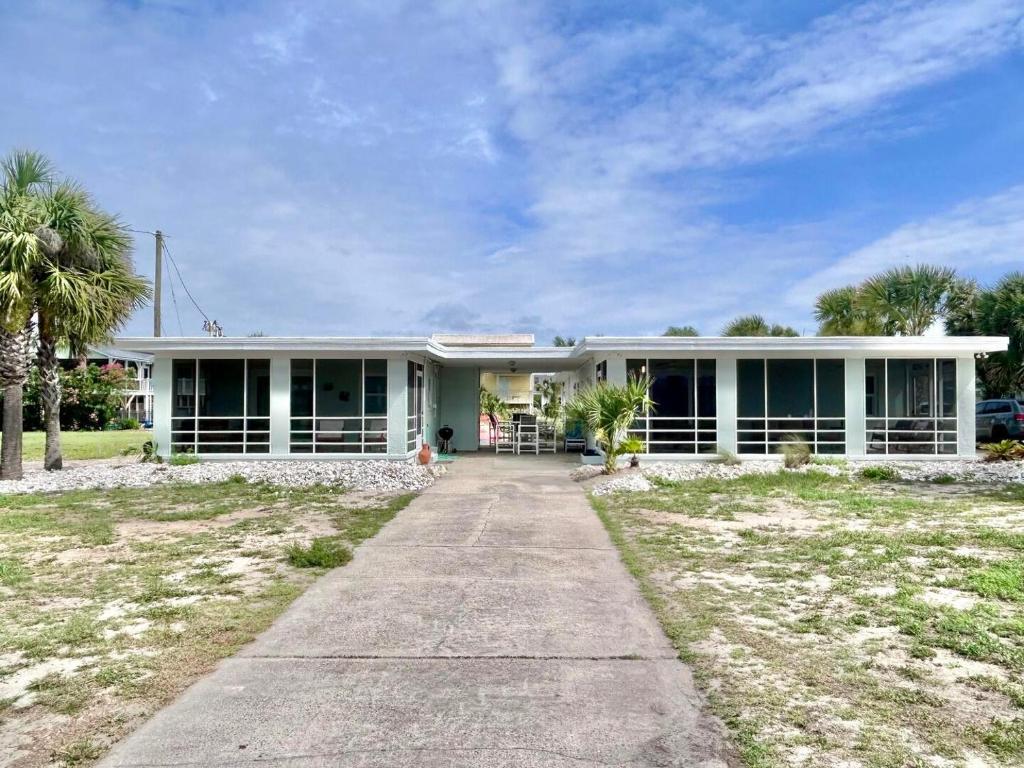 a large white house with a palm tree at Baked and Barefoot Beach Bunglows in St. George Island