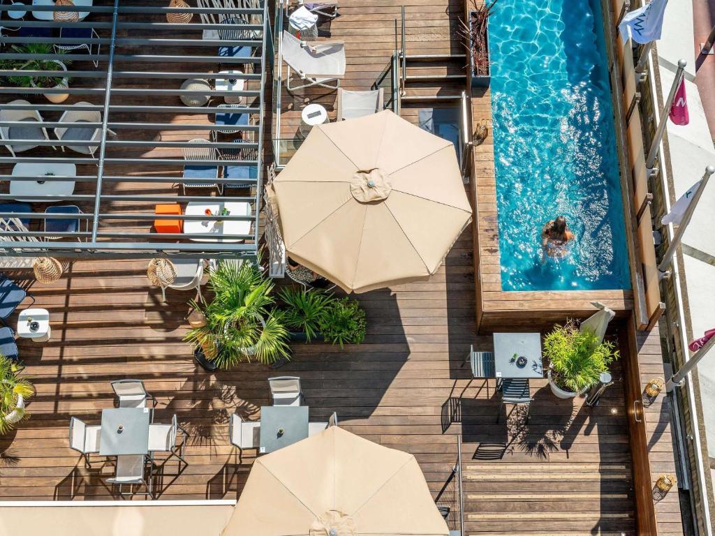 an overhead view of a swimming pool with umbrellas and chairs at Mercure Toulouse Centre Saint-Georges in Toulouse