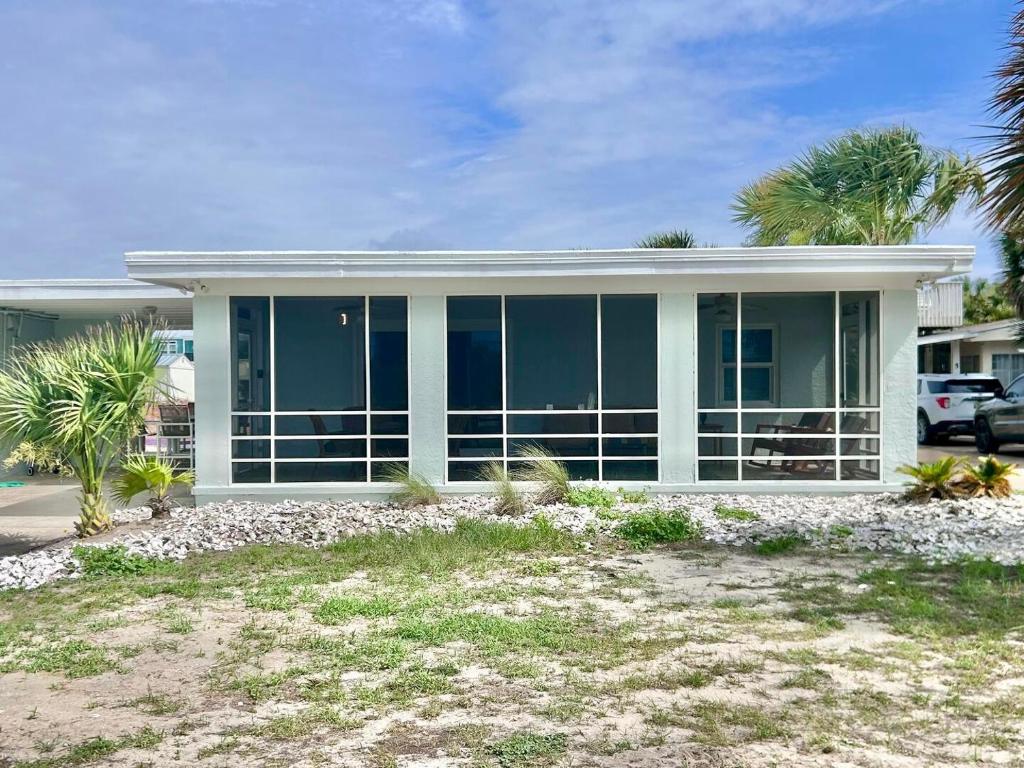 a house with large glass windows and palm trees at Barefoot Beach Bungalow-Ground Level-3BR in St. George Island