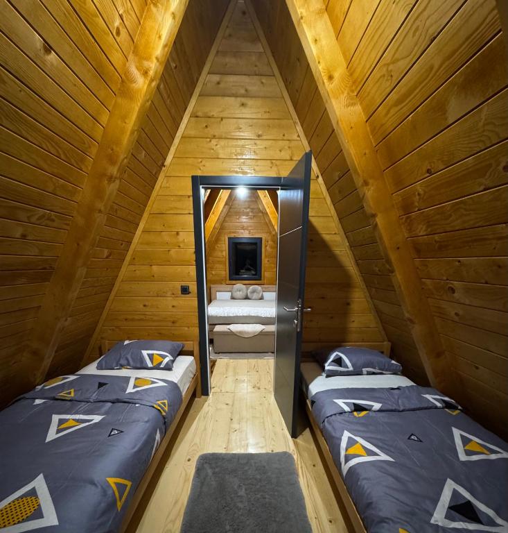 two beds in a room with a tv in a attic at Vila Kalkan in Šipovo