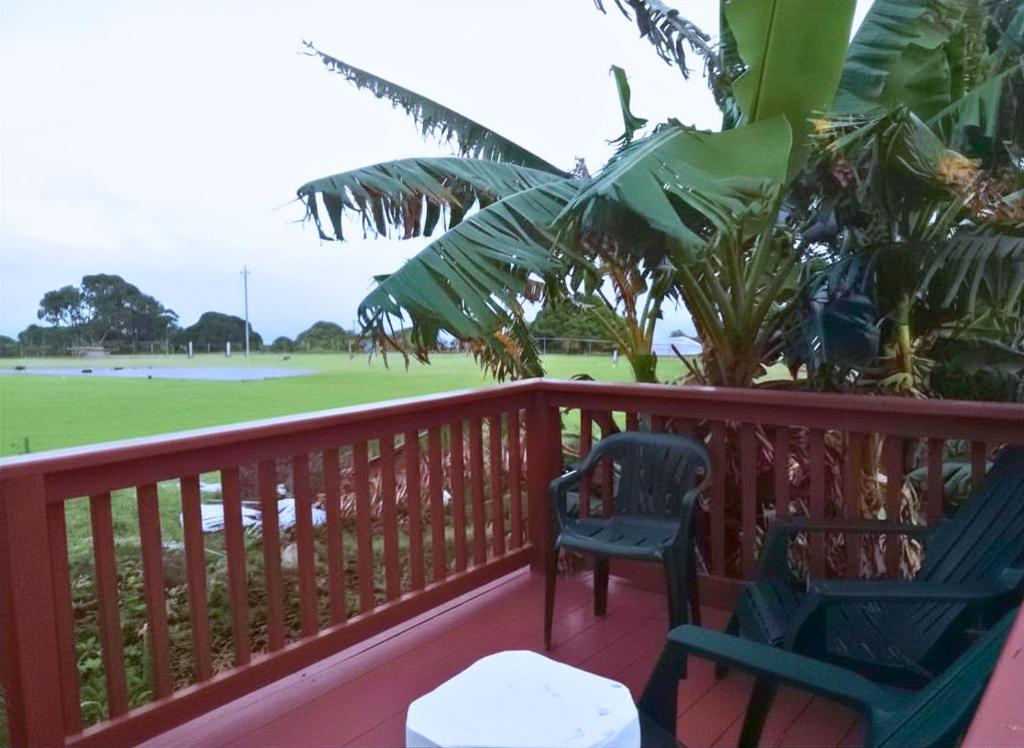 two chairs sitting on a deck with a baseball field at Good Times in Gingerland