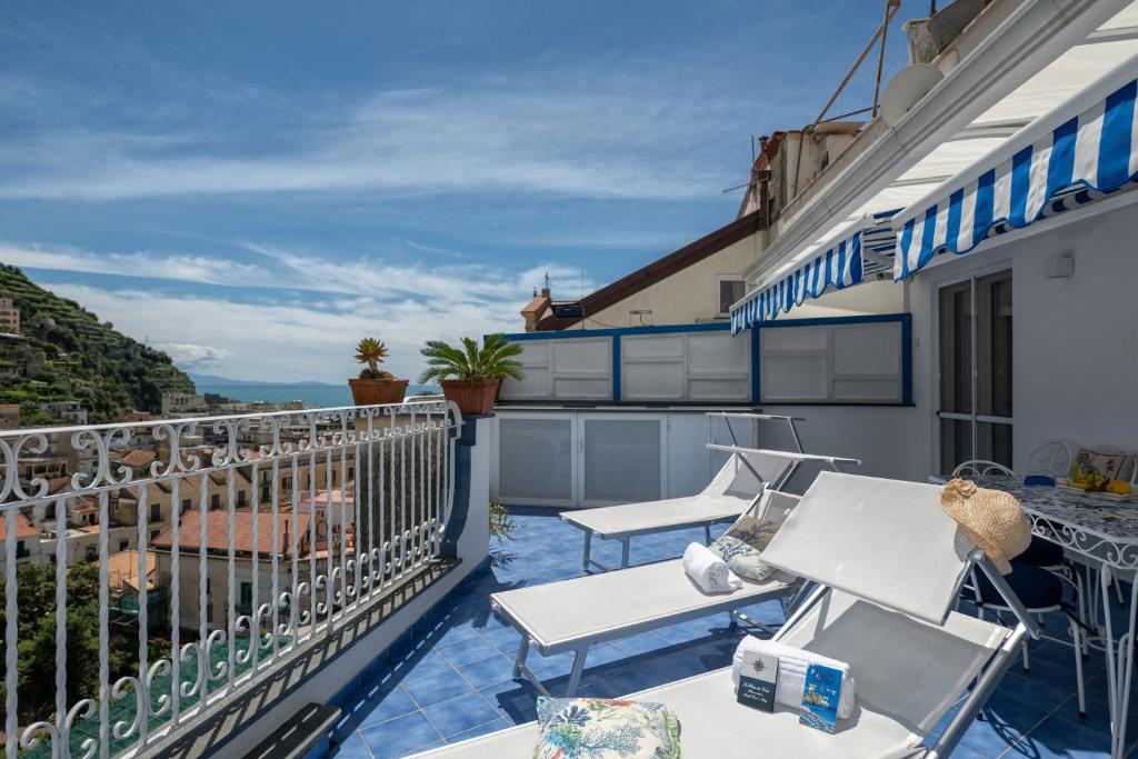 a balcony with chairs and tables on a building at Grecale - stunning sea-view apartment with patio, up to 5 guests in Maiori