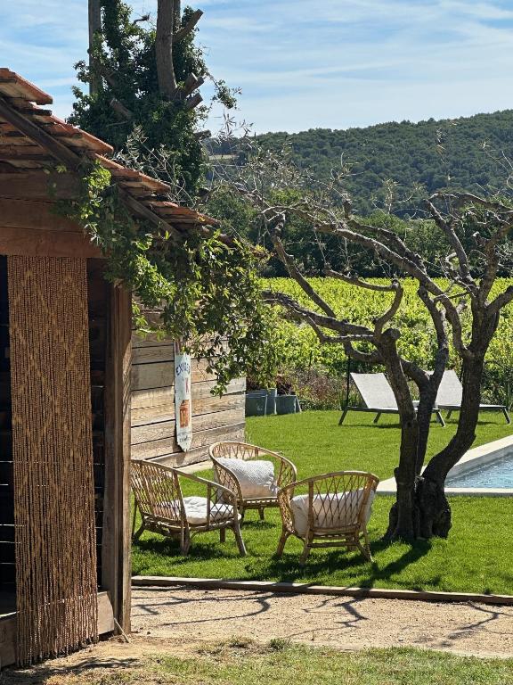 two benches sitting next to a tree next to a pool at Le Grand Gîte in Vaison-la-Romaine