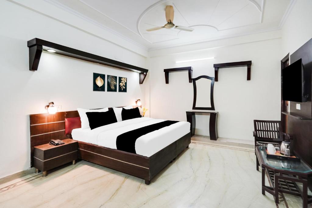 a bedroom with a black and white bed and a tv at HOTEL O 4 SQUARE A LUXURY ROOMS NEAR RDC MAIN MARKET in Ghaziabad