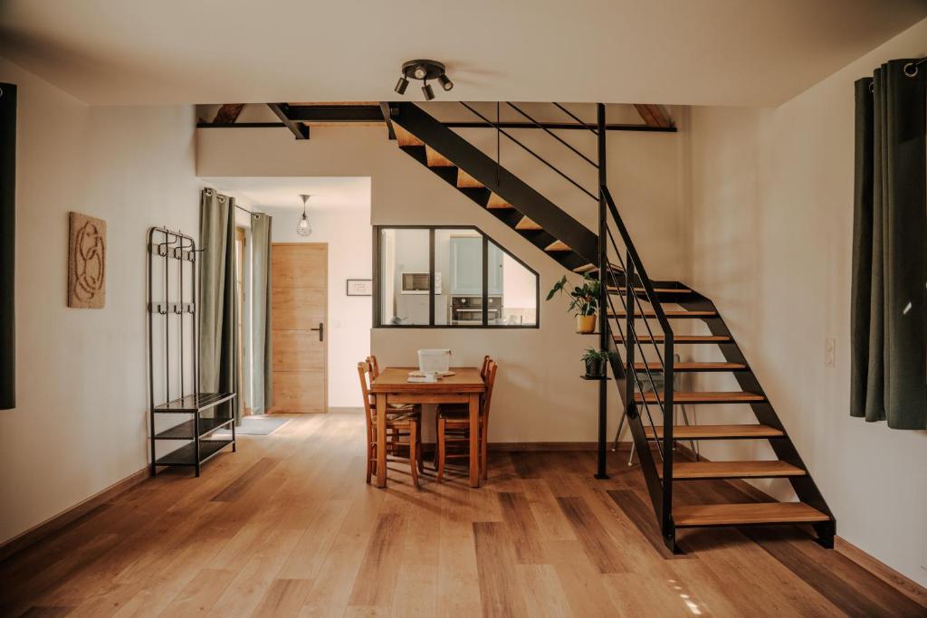 a living room with a wooden table and a spiral staircase at Le loft de Marthe in Bonnières