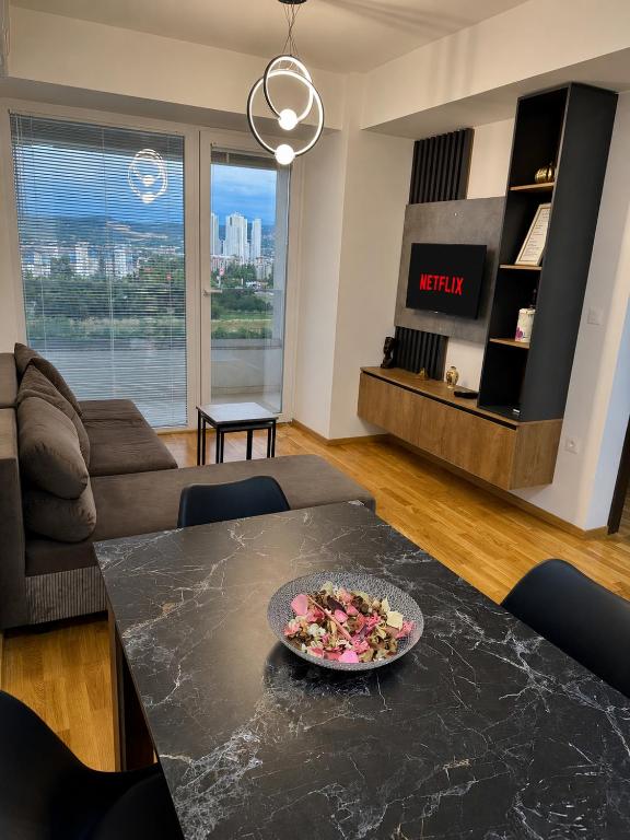 a living room with a table with a plate of food on it at Skyline Apartment Skopje in Madžari