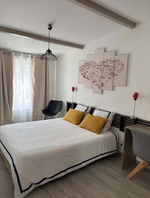 a bedroom with a large white bed with yellow pillows at L Olivier in Nanterre