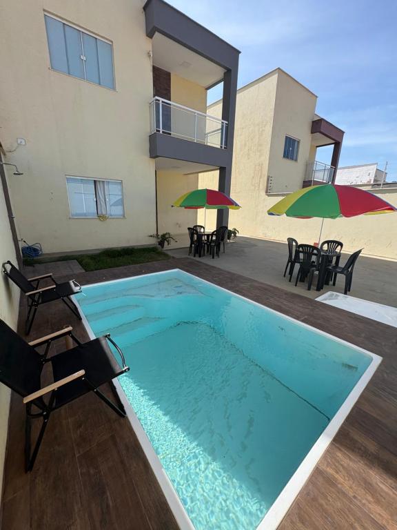 a swimming pool in front of a house with chairs and umbrellas at CASA COM PISCINA ATE 16 PESSOAS 700mts da praia do aracagy in São Luís