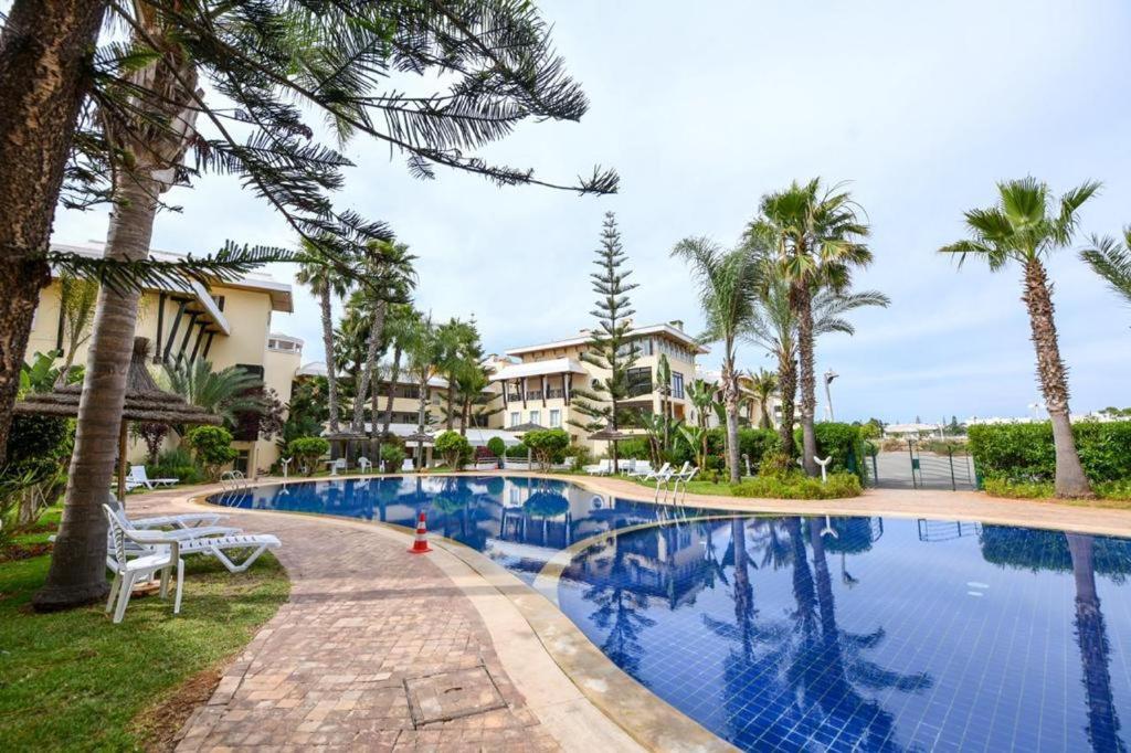 a pool at the resort with palm trees and condos at Spacious apartment, pool, beach, basement parking in Bouznika