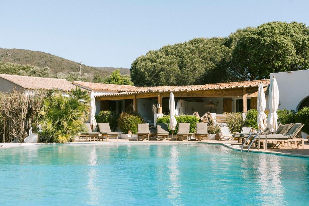 a pool at a resort with chairs and umbrellas at Hôtel Palombaggia in Porto-Vecchio