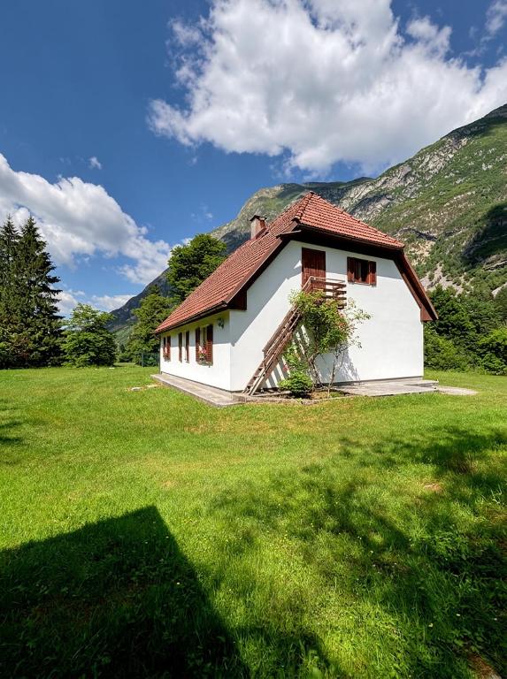 a small white house in a field with mountains at House Flajs - secluded 2BR Surrounded by Forest in Soča