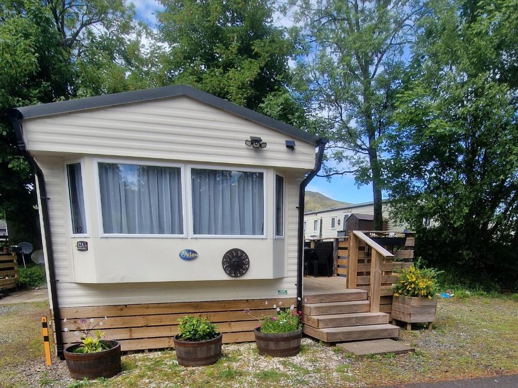 a tiny house with a porch and stairs in a yard at Forest Valley Holiday Home in Ballantrae