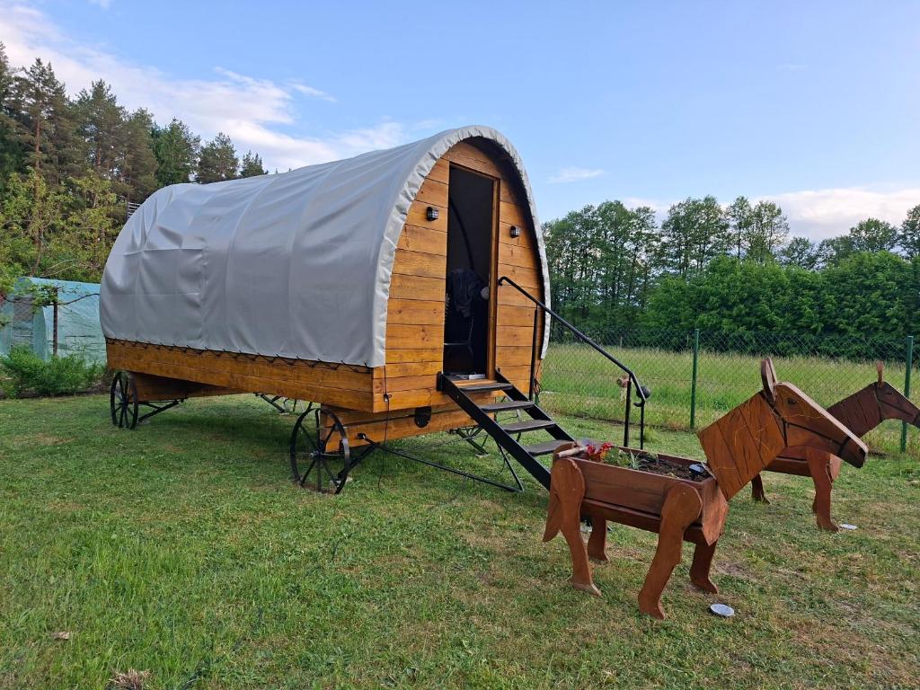 a small wooden tent with a horse and a cart at Czarci Zakątek in Pozezdrze
