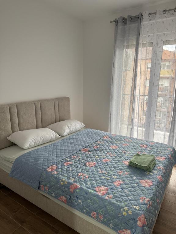a bed with a blue comforter with a bag on it at Apartman 38 in Stara Pazova