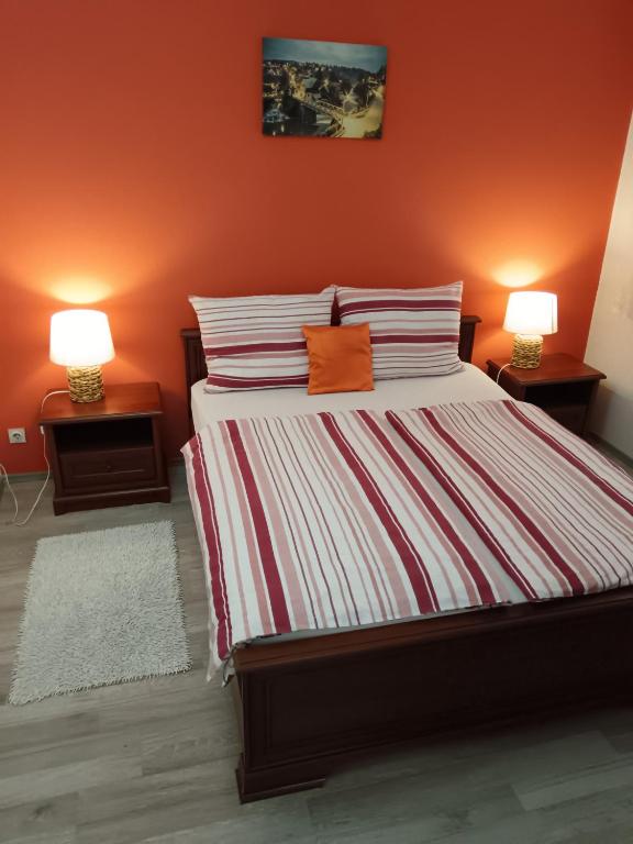 a bedroom with a bed with orange walls and two lamps at Apartman Drenovac in Slunj