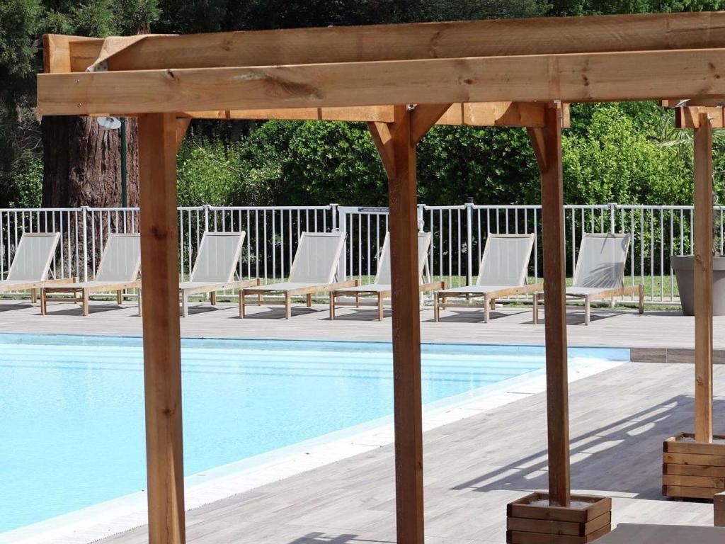 a wooden pavilion next to a pool with lounge chairs at Hotel Mercure Parc du Coudray - Barbizon in Le Coudray-Montceaux