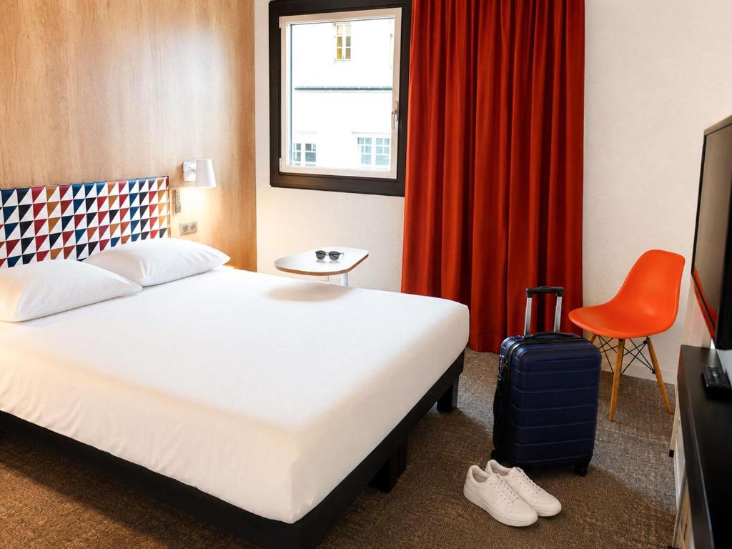 a hotel room with a bed and a red curtain at ibis Styles Caen Centre Historique in Caen