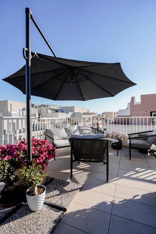 a patio with an umbrella and some chairs and flowers at Central Penthouse with massive terrace in San Ġwann