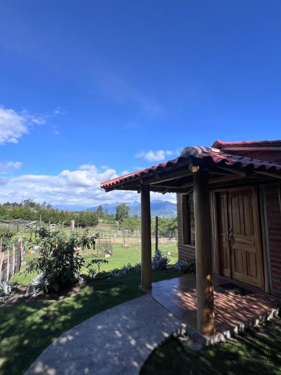 a house with a porch with a view of a field at Refugio del venado familiar in Cotacachi