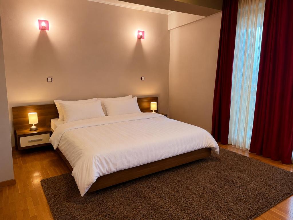 a bedroom with a large white bed with two lamps at King Apartment Bucharest in Dudu