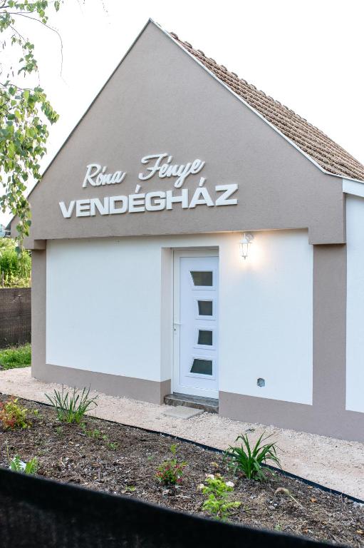 a garage with a white door and a sign on it at Róna Fénye Vendégház in Sándorfalva