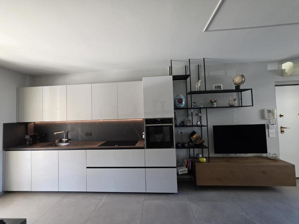a kitchen with white cabinets and a flat screen tv at Casa Alma in Lido di Fermo