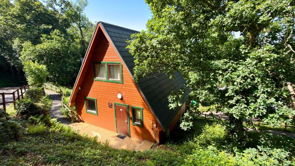 a small orange house with a black roof at Lazy Bear Lodge with Hot Tub - Finlake Resort and Spa in Devon in Chudleigh