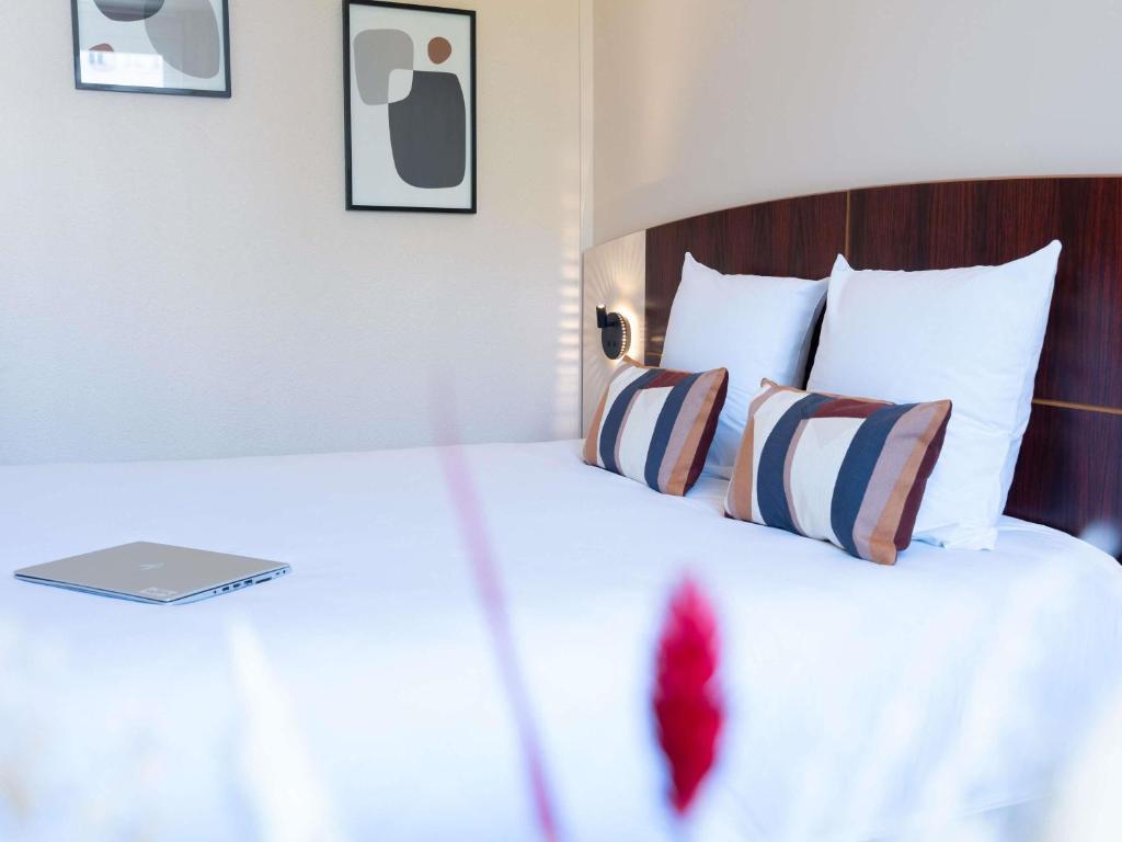 a bedroom with a bed with a laptop on it at Mercure Besancon Parc Micaud - Hotel & Bar in Besançon