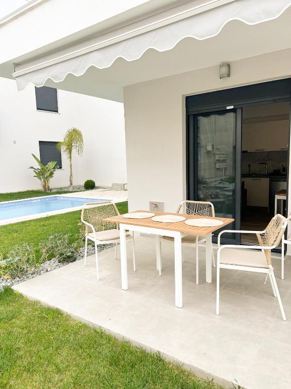 a table and chairs on a patio with a pool at Sea Shell Apartment - Paralia Ofriniou, Swimming pool, Starlink WIFI in Orfánion