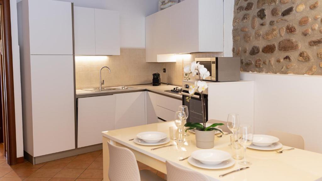 a kitchen with white cabinets and a table with chairs at Gomes Comfort House Borghetto in Valeggio sul Mincio