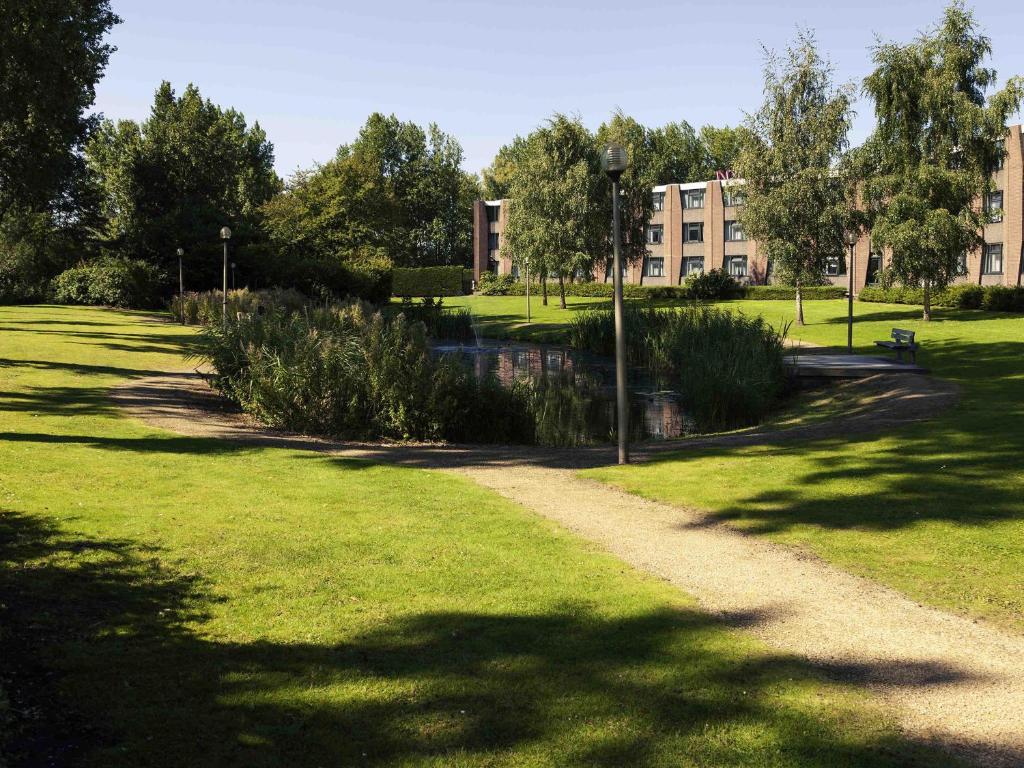 a path in a park with a building in the background at Mercure Hotel Amsterdam West in Amsterdam