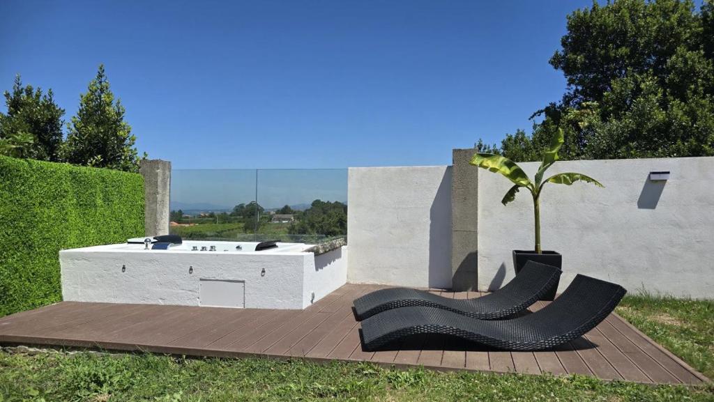 two black chairs and a tree on a patio at Casa rural Villa Quintans in Soutullo