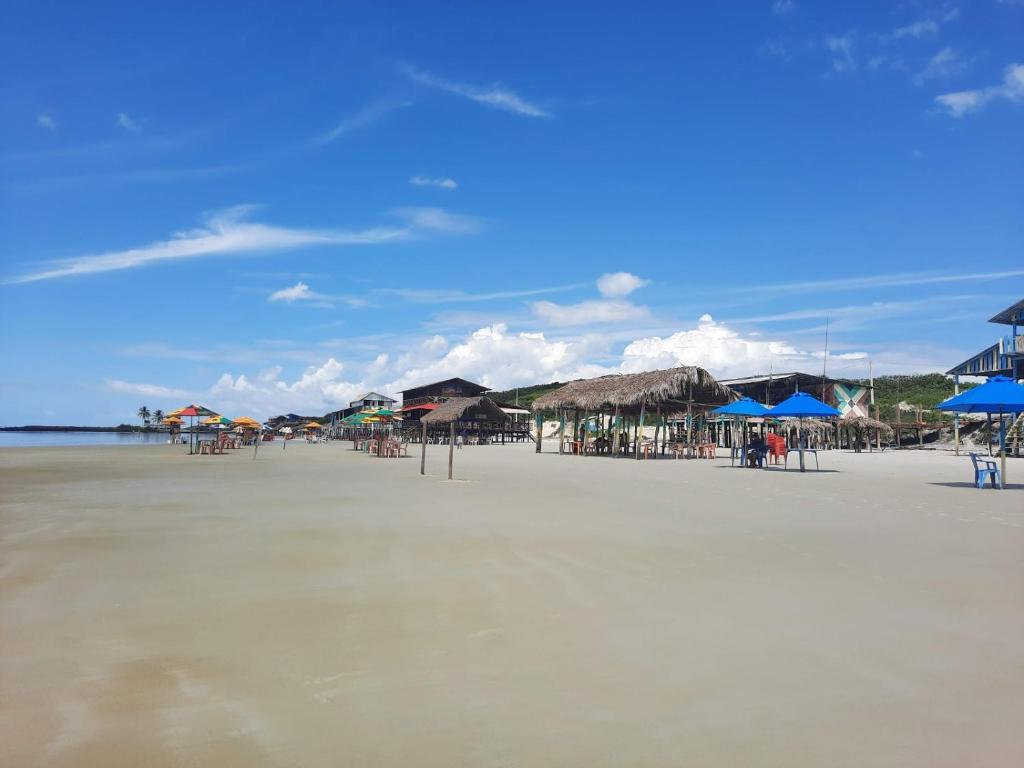 a beach with tables and umbrellas on the sand at Pousada e Restaurante Chateau Soneka in Algodoal