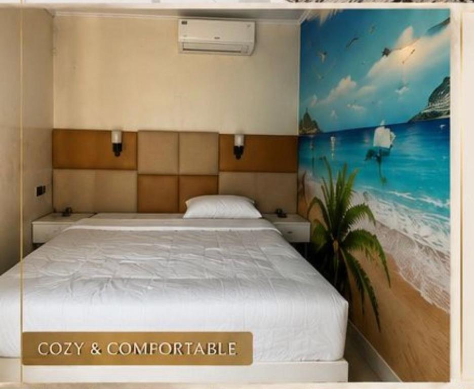 a bedroom with a bed with a painting on the wall at Ege Inn in Guraidhoo