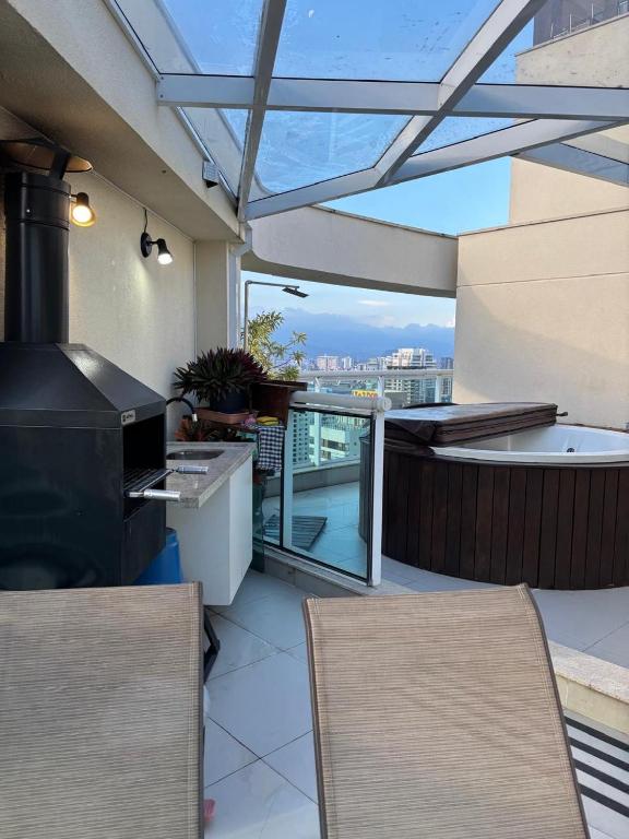 a patio with a grill and chairs on a balcony at Santos Unique 2701 Jacuzzi & Sea View Duplex in Santos