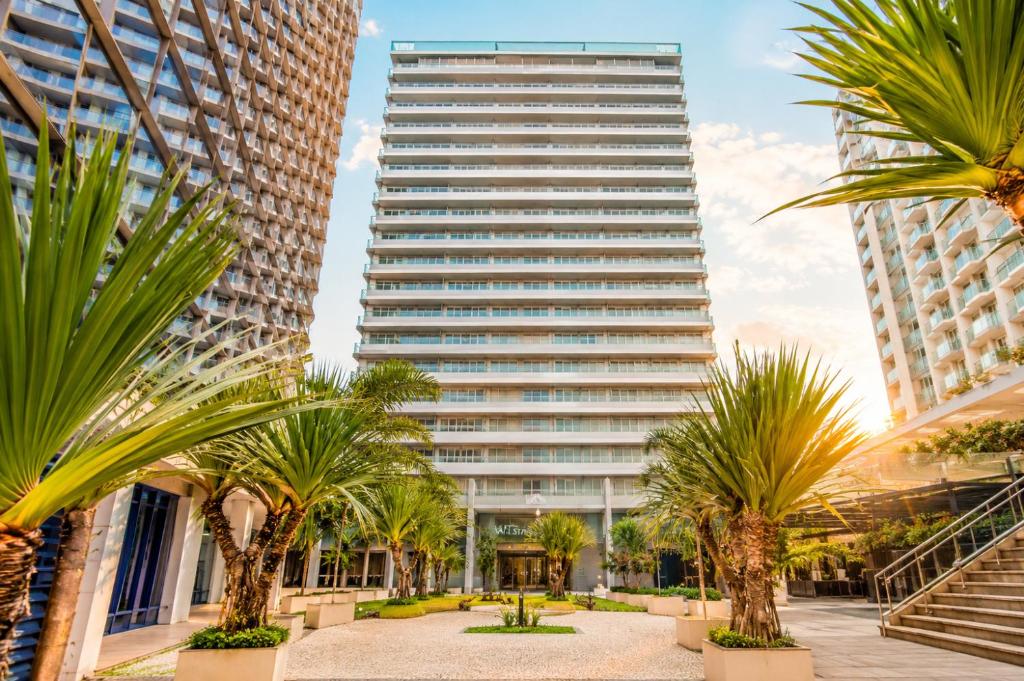 a tall building with palm trees in front of it at Alugueasy - Hotel Vision in Brasília