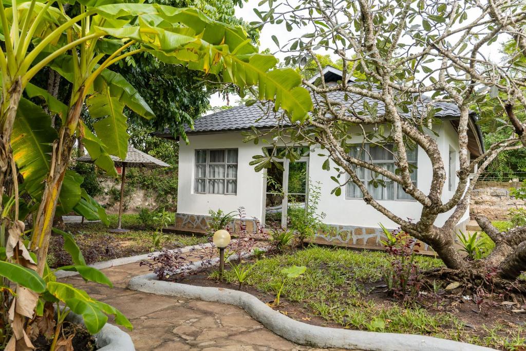 a white house with a tree in front of it at Auregi Villas in Diani Beach