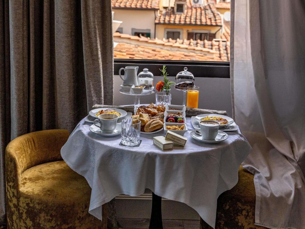 a table with plates of food and drinks on it at Cerretani Hotel Firenze - MGallery Collection in Florence