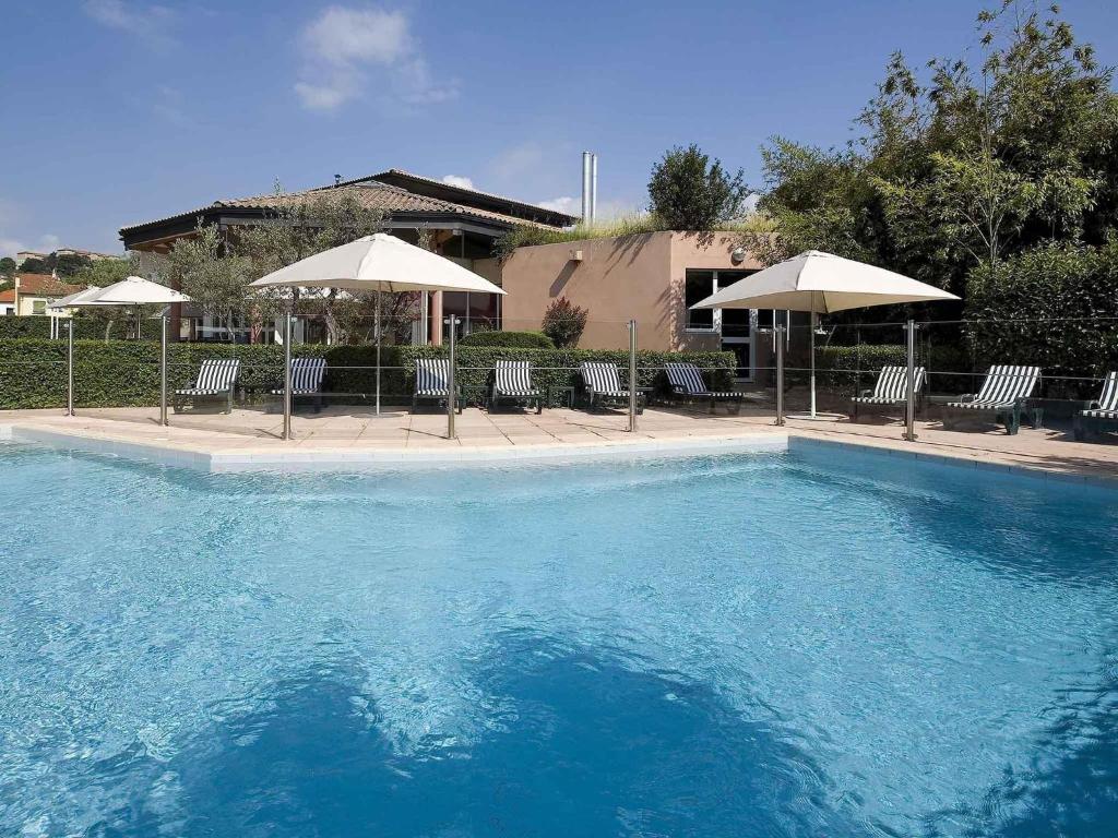 a large swimming pool with chairs and umbrellas at ibis Aubenas in Aubenas
